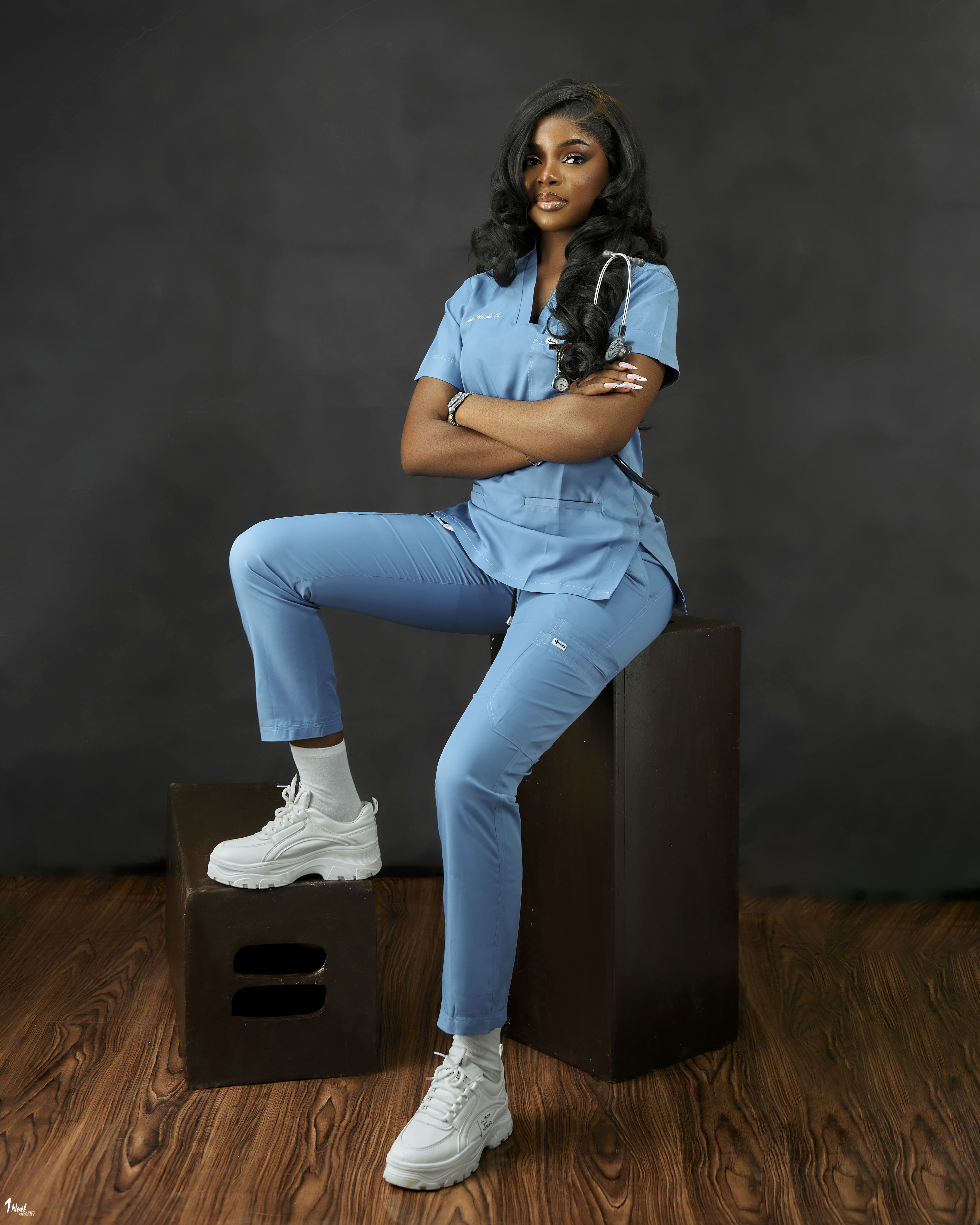 Chisom Nwodo seated in blue nursing scrubs
